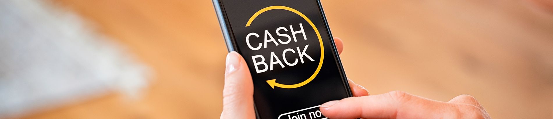 Foto das mãos de uma pessoa segurando um celular com a palavra cashback